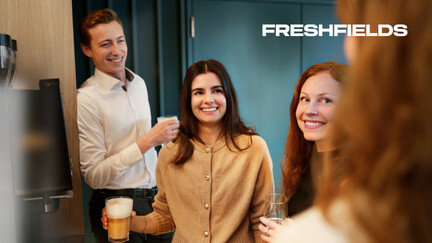 Auf dem Bild sieht man rechts oben das Logo von Freshfields und darunter eine Szene von Kolleginnen und Kollegen in jungem Alter bei der Kaffeepause im Gespräch