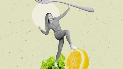Ein Mädchen steht auf einem Salatblatt und hält eine überdimensionierte Gabel in der Hand