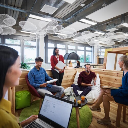 Mehrere junge Menschen sitzen in einem modernen Coworking-Space